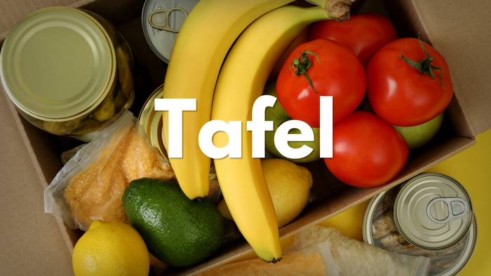 Eine Pappkiste gefüllt mit frischem Obst, Gemüse und Konserven mit der Aufschrift „Tafel“.