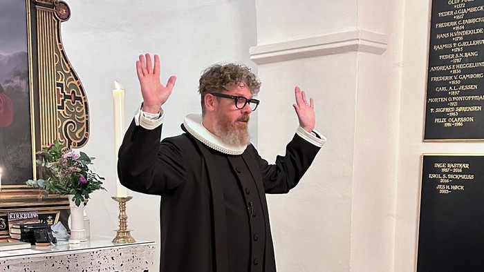 Mand i svart kapittel i kirke.