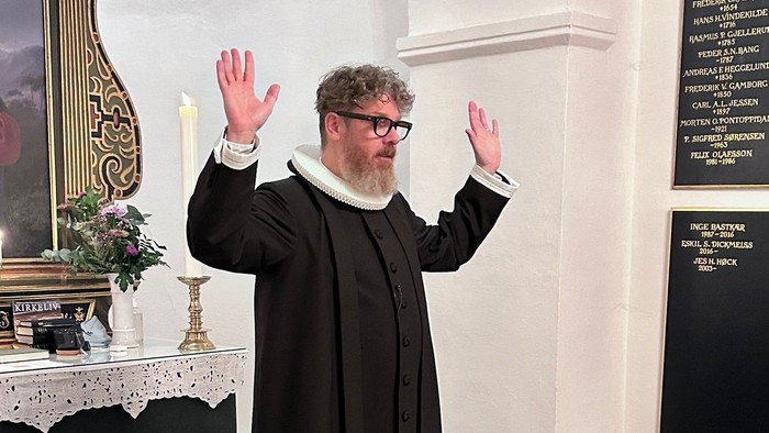 Mand i svart kapittel i kirke.