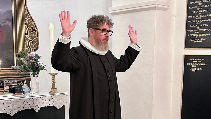 Mand i svart kapittel i kirke.