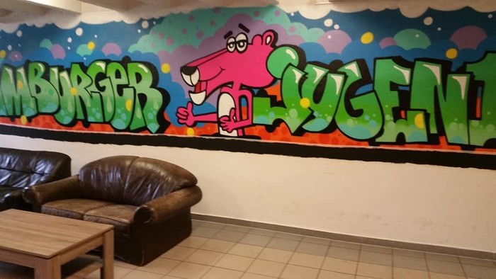 Bunter Graffiti-Wand in einem Raum mit braunem Sofa