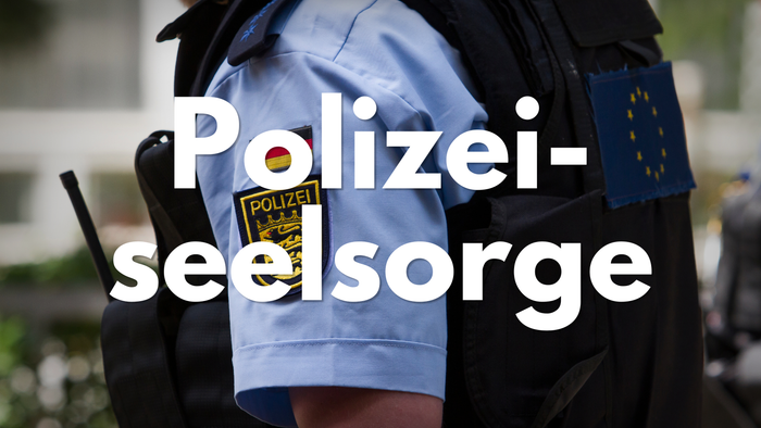 Polizeibeamter mit einer Weste mit dem Aufnäher „Polizei-Seelsorge“ und EU-Flagge, was auf seelsorgerische Betreuungsdienste hinweist.