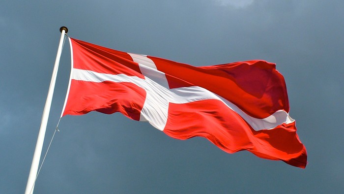 Rødt flag med hvidt kors flyver i vinden