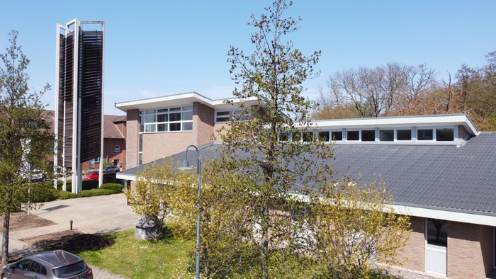 Modernes Gebäude mit hoher Säule und parkähnlichem Garten