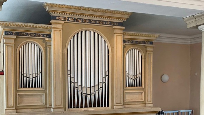 Das Bild zeigt eine große Kirchenorgel mit verzierten Holzpaneelen und Pfeifen.