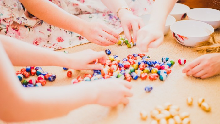 Kinder sortieren bunte Süßigkeitenstücke und kleine Spielzeuge auf einem Tisch während einer lustigen Aktivität.