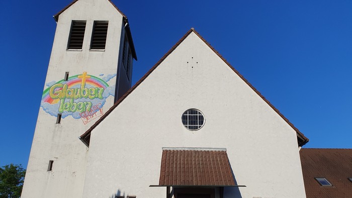 Weiße Kirche mit buntem Schild, klarer blauer Himmel