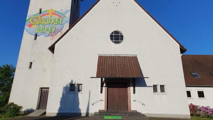 Weiße Kirche mit buntem Schild, klarer blauer Himmel