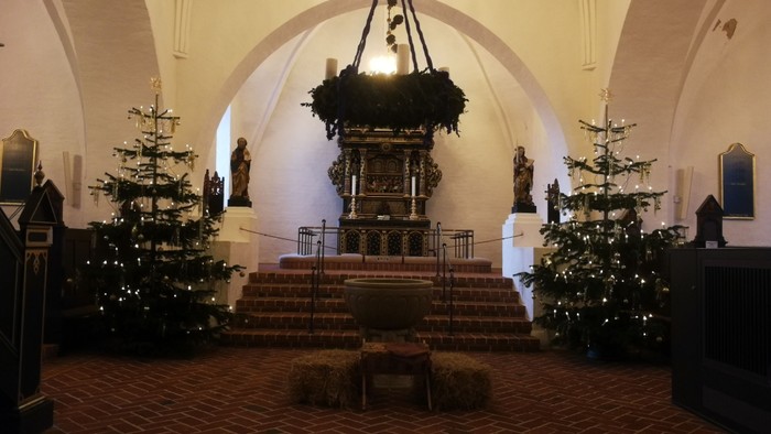 Indre del af kirke med juletømmer og alter.