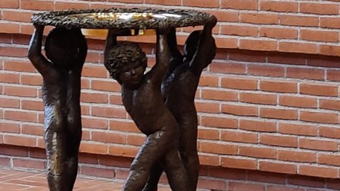 Bronzefigur af to børn, der bærer en plate på et murstenvægge
