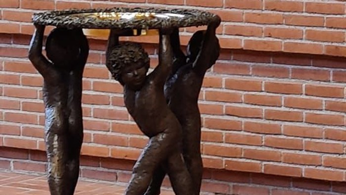 Bronzefigur af to børn, der bærer en plate på et murstenvægge