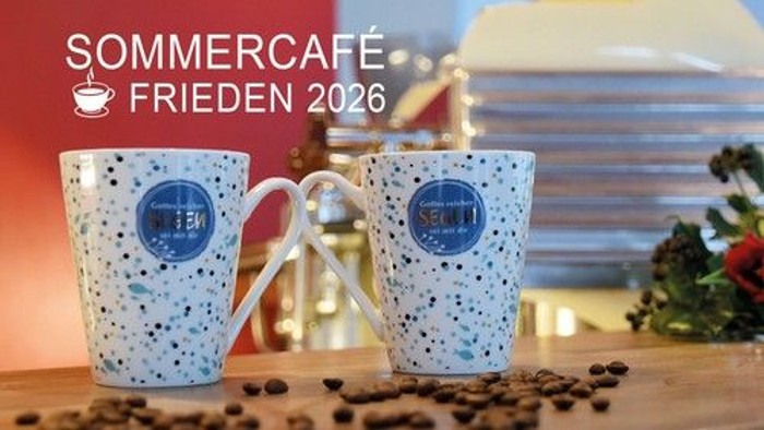 Verzierte Kaffeetassen mit der Aufschrift „Sommercafé Frieden 2026“, Kaffeebohnen und einem festlichen Hintergrund.