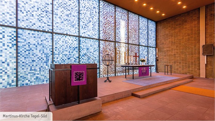 Modernes Kircheninnere mit großen Glasfenstern und Holzpulten