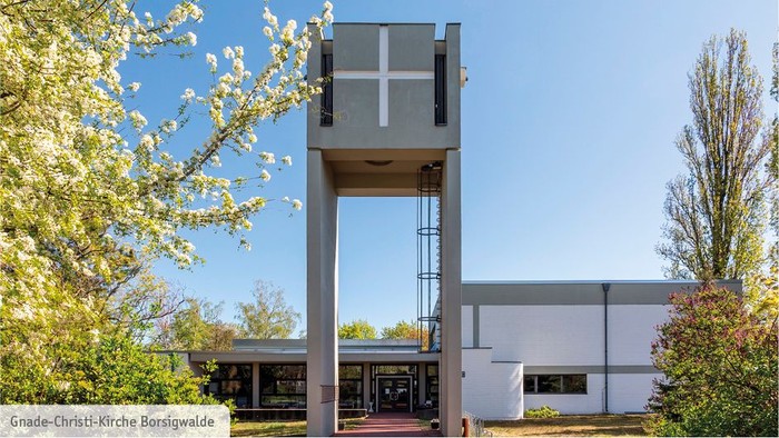 Moderne Kirche mit hohem Turm und blühenden Bäumen