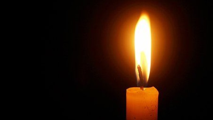 Eine einzelne Kerzenflamme leuchtete hell vor dunklem Hintergrund.