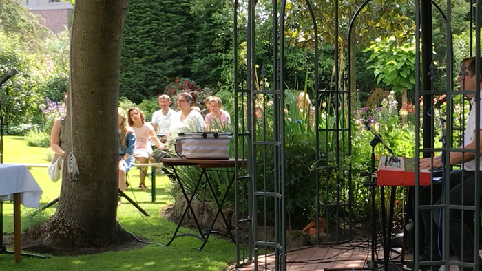 Im Garten sitzen Menschen an Tischen, es ist ein Treffen oder Event.