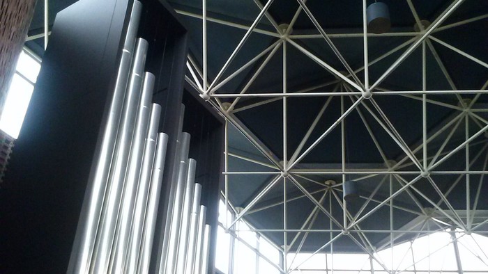 Moderne Kirche mit freitragender Deckenkonstruktion und Orgel.