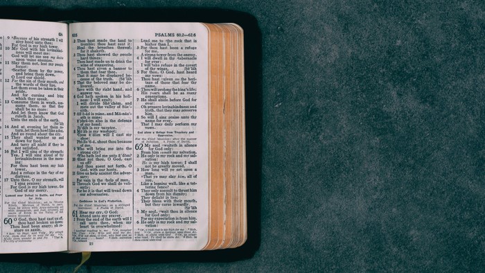 Eine offene Bibel mit sichtbarem Text auf den Seiten, die auf einer strukturierten Oberfläche liegt.