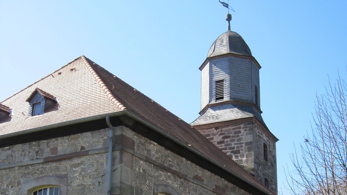Außenansicht der evangelischen Kirche in Oberelsungen. Das Gebäude besteht aus hellem Naturstein mit hohen Fenstern.