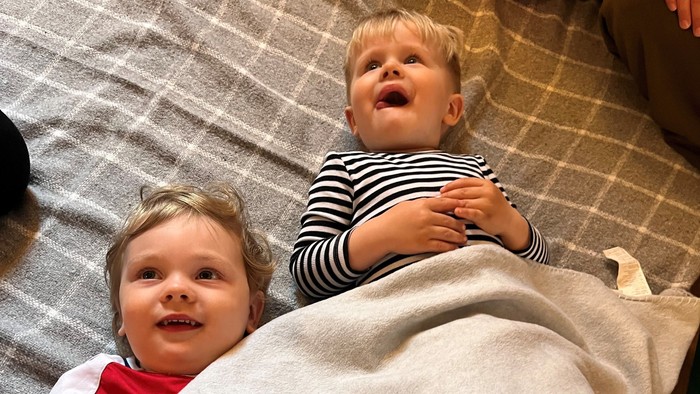 To børn ligger på tæppe og lytter
