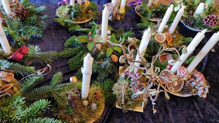 En festligt dekoreret bord med grønne planter, lysstaker og smykker.