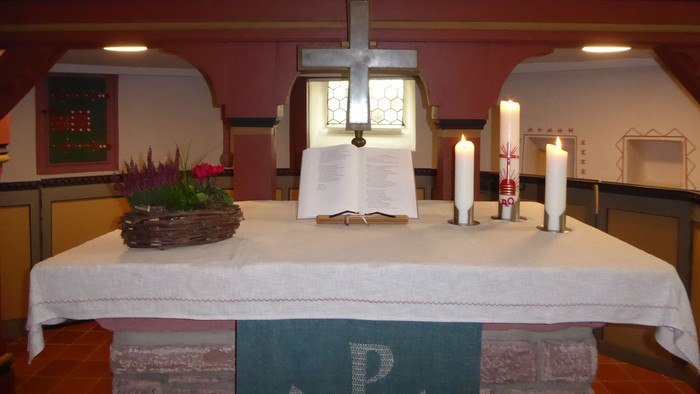 Altar mit Kreuz, Kerzen und Blumen in der Kirche