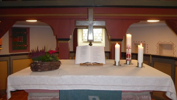 Altar mit Kreuz, Kerzen und Blumen in der Kirche