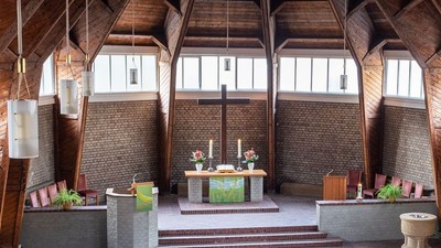 Ein moderner Wohnraum mit hohen Decken und großen Fenstern, eingerichtet mit Holz und grünen Akzenten.