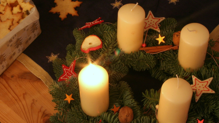 En juledekoreret skovfrø med tre lysende lygter, nødder, og stjerner.