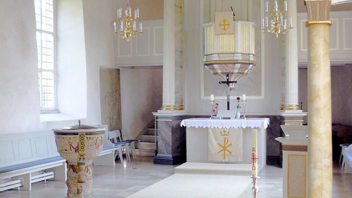 In der Kirche hängen goldene Kronleuchter, und blaue Bänke sind ordentlich angeordnet.