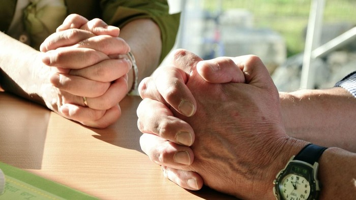 To hands holdes hinanden på bordet