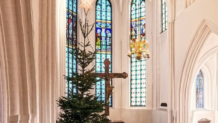 Kirkeinteriør med juletræ og farvede glasvinduer