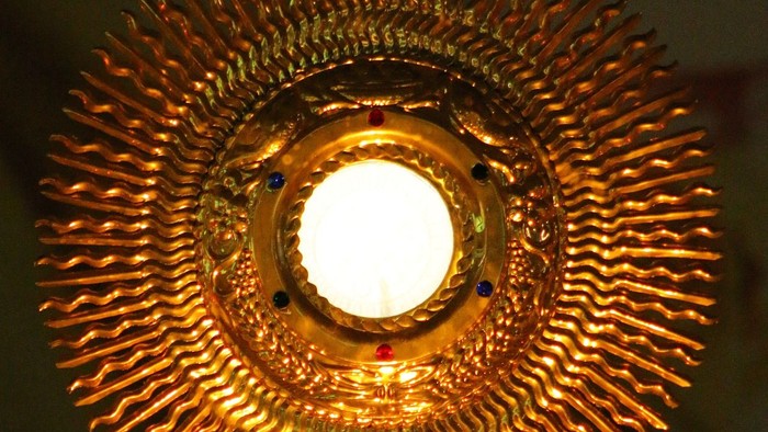 Goldener Leuchter mit Kreuz und hellen Licht.