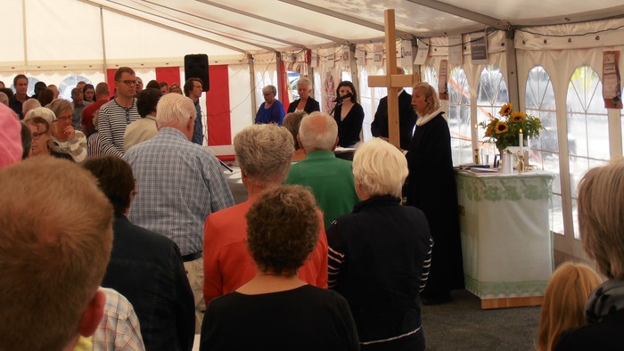 En gruppe mennesker deltager i en religiøs ceremonie under et telt.