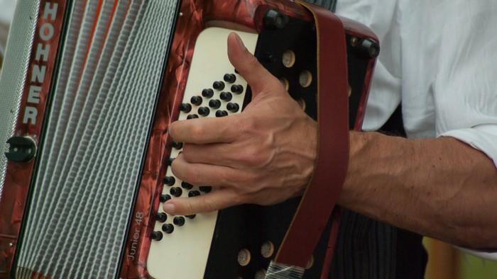 Ein Akkordeon, die schwarzen Knöpfe auf Elfenbein, eine Hand