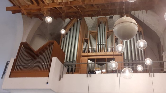 Große Kirchenorgel mit Holzpfeifen und Kronleuchtern in einem hohen Gewölbe.