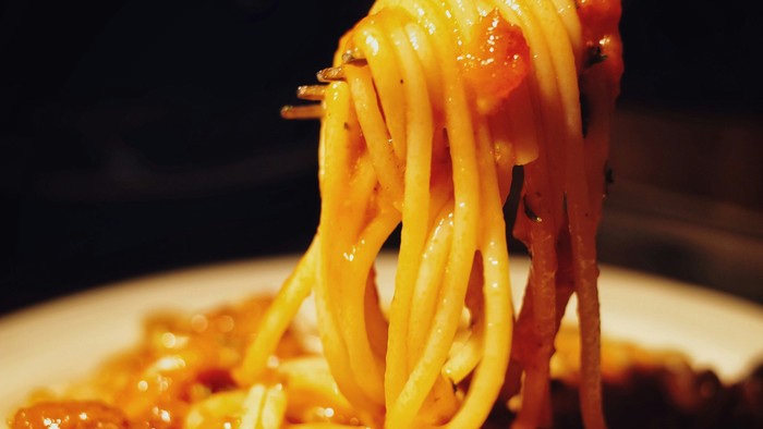 En gabel med spaghetti i tomatsoace.