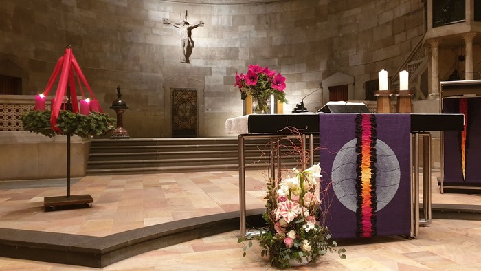 In der Kirche stehen bunte Blumenarrangements und ein Kruzifix an der Wand.