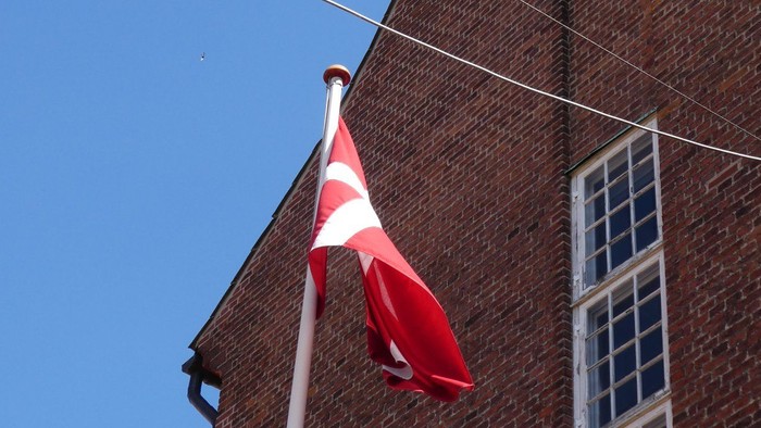 En rød flag med hvid skive på en stang foran et murstenshus