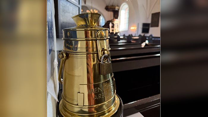 En gylden klokke med et prangende design udstillet indendørs på en reflekterende overflade.