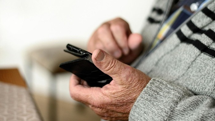 Ältere Hand hält Smartphone