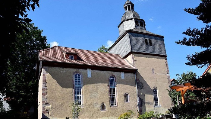 Kirchengebäude mit hohem Turm und rotem Dach unter blauem Himmel