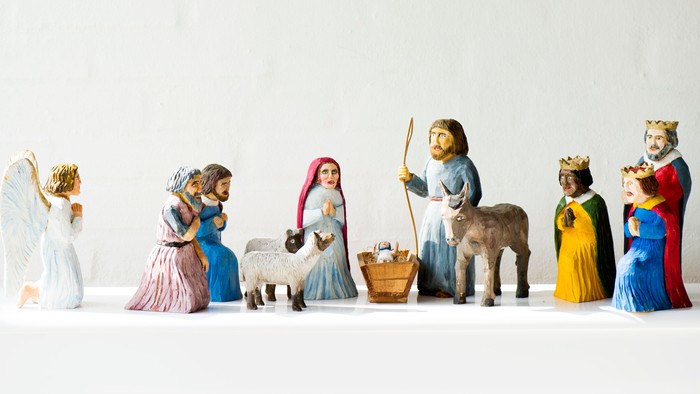 En rekke figurer af julemandspiger i farverne blå, guld og rød, med en engel og et dyr.