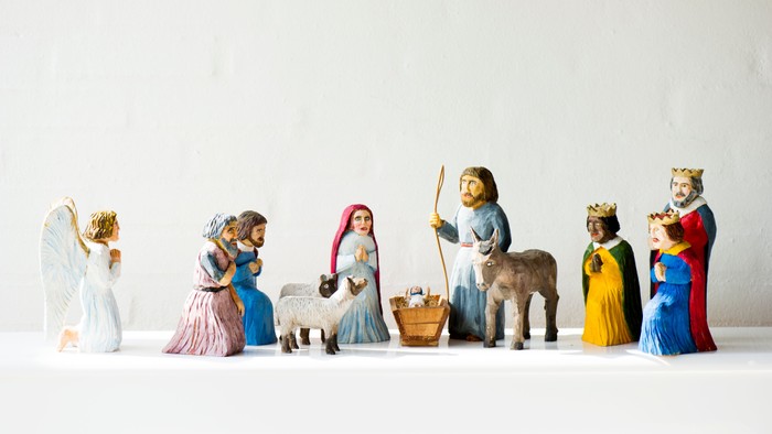 En rekke figurer af julemandspiger i farverne blå, guld og rød, med en engel og et dyr.