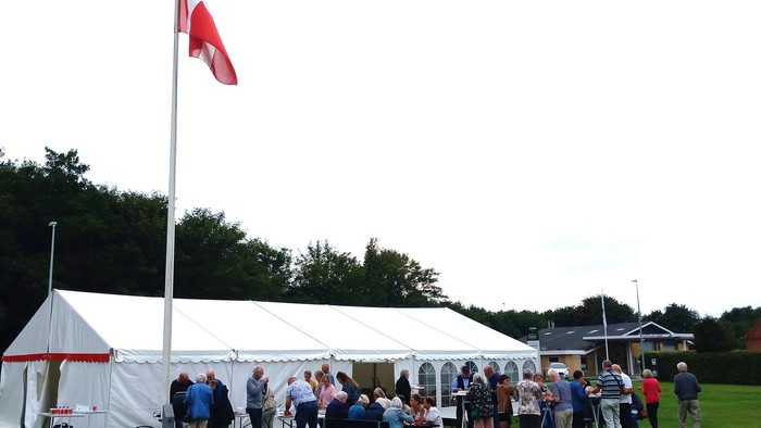 Fest telt. Flag, mennesker der står og spiser og snakker