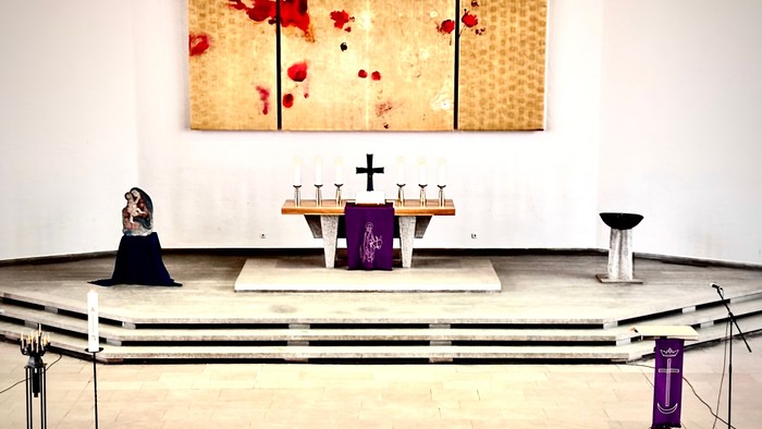 Minimalistisches Kapelleninneres mit Altar, Glasmalerei-Kunst und schlichter Sitzanordnung.