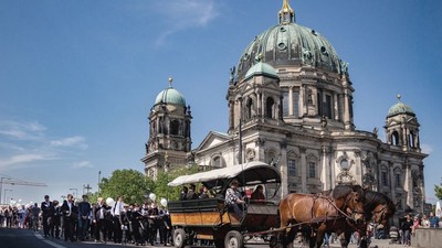 Pferdewagen fährt vor großer Kirche, viele Menschen stehen herum