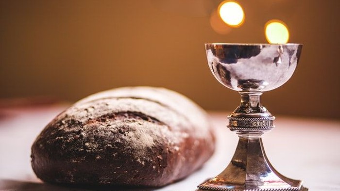 Silbernes Kelch und Brot auf Tisch