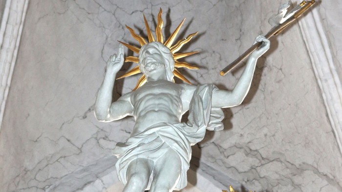 Eine strahlende Engelsstatue hält einen goldenen Sonnenstrahl, verziert in einem prunkvollen architektonischen Torbogen.