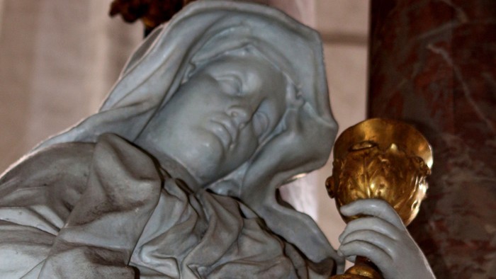 Die Statue einer Frau hält eine goldene Vase.